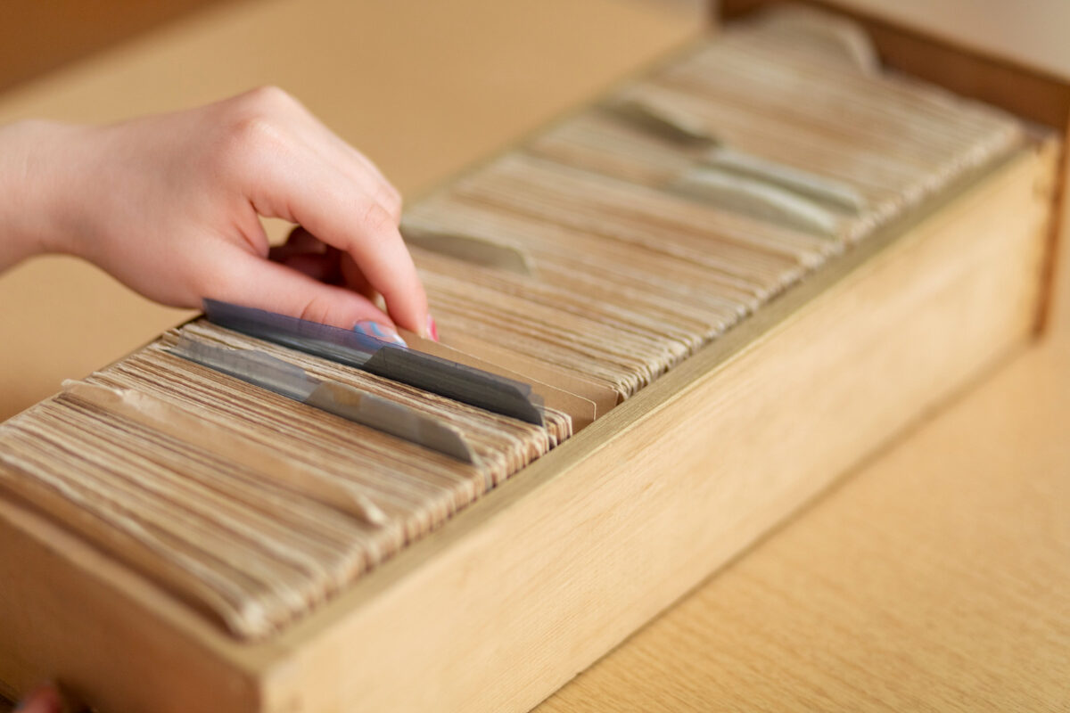 A hand in a wooden card-catalog drawer